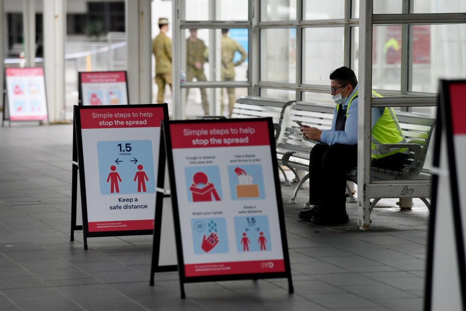 Social distancing signs at Sydney Airport and worker wearing face mask during coronavirus lockdown.