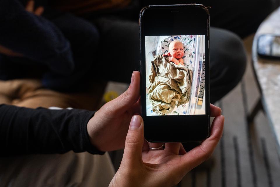 Emily Donlin holds photos from her second son's first days in the hospital, Tuesday, Dec. 5, 2023, in Des Moines. After his birth, the umbilical cord was screened in a nonconsensual drug test, which came back positive for cocaine. The family claims the test results were a false positive.