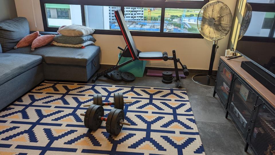 A picture of a living room with a couch, dumbbells and a bench. (Photo: Yahoo Lifestyle Singapore)