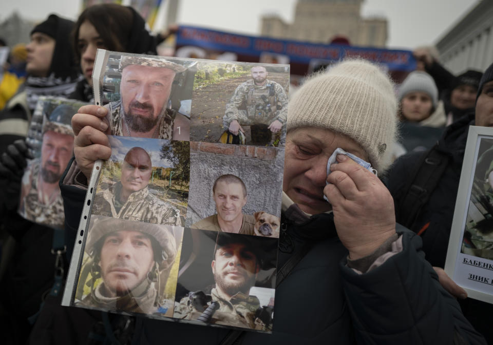 Ukrainian mother Valentina Diachuk, 59, holds a picture of her missing son Mykola Diachuk and his brothers-in-arms during a demonstration in downtown Kyiv, Ukraine, Saturday, Jan. 14, 2023. (AP Photo/Bela Szandelszky)