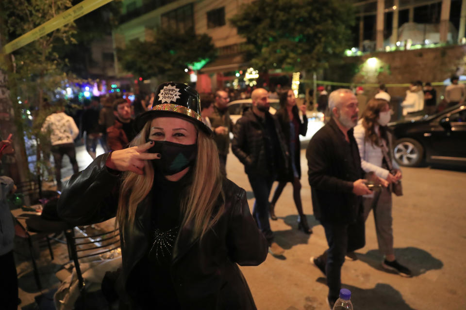 A Lebanese woman wears a protective mask to prevent the spread of coronavirus, as she celebrates the New Year outside a pub, in Beirut, Lebanon, early Friday, Jan. 1, 2021. Lebanon ended the year with more than 3,500 newly registered infections of coronavirus and 12 new deaths as its health minister appealed to Lebanese to take precautions while celebrating to avoid what he called wasting sacrifices made in combatting the virus. (AP Photo/Hussein Malla)