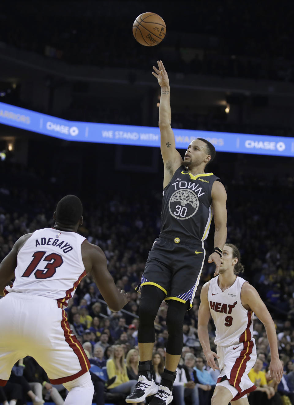 Golden State Warriors' Stephen Curry (30) shoots between Miami Heat center Bam Adebayo (13) and Kelly Olynyk (9) during the second half of an NBA basketball game, Sunday, Feb. 10, 2019, in Oakland, Calif. (AP Photo/Ben Margot)
