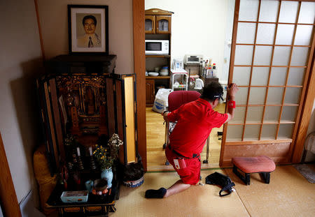 Congenital Minamata disease patient Koichiro Matsunaga holds onto a door to stand up next to the altar for his father at his home in Minamata, Kumamoto Prefecture, Japan, September 13, 2017. REUTERS/Kim Kyung-Hoon