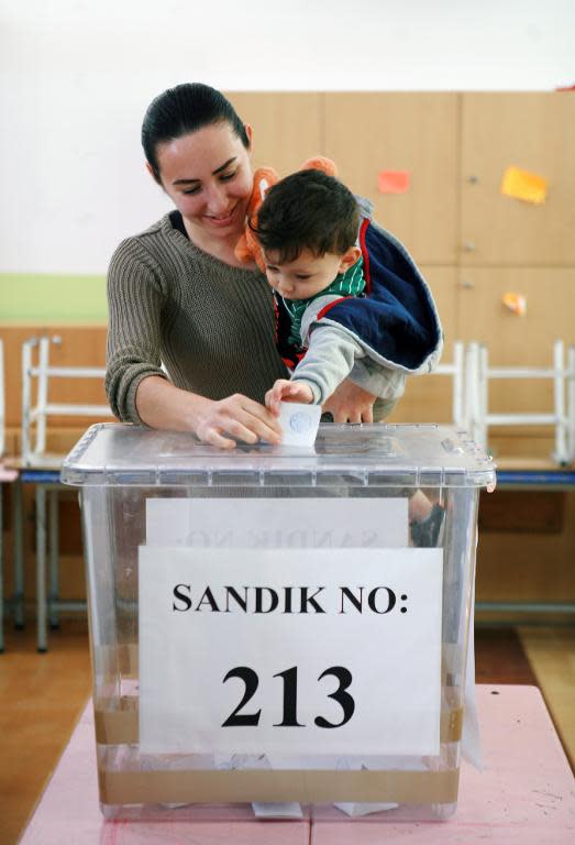 A Turkish Cypriot woman holding her baby casts her vote at a polling station in the northern part of Nicosia during the second round of the presidential elections in the self-proclaimed Turkish Republic of Northern Cyprus (TRNC) on April 26, 2015