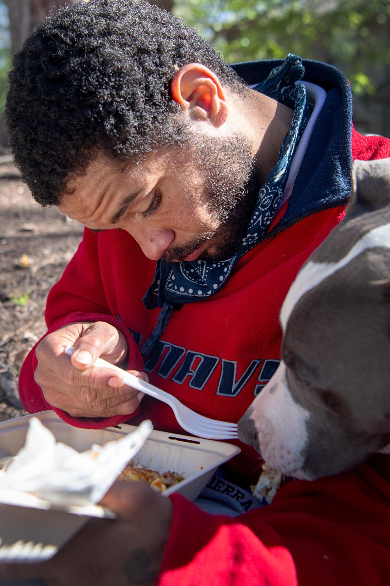 Reginald Bolden, Jr. shares his breakfast with his dog, Smoke, at ABCCM in Asheville, April 13, 2024. “It’s hard,” said Bolden of living on the street, though he finds solace in the bond he has with his canine partner. “It’s like a father holding their child for the first time, it’s the greatest feeling.”