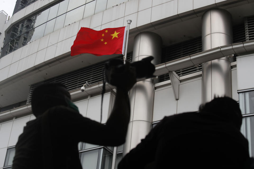 Journalists take picture and video over the water-filled barriers after an opening ceremony for China's new Office for Safeguarding National Security in Hong Kong, Wednesday, July 8, 2020. China's new national security office in Hong Kong got off to an early start on Wednesday with an official opening amidst heavy police presence. (AP Photo/Kin Cheung)