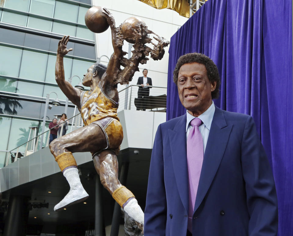 FILE - Elgin Baylor stands next to a statue, just unveiled, honoring the Minneapolis and Los Angeles Lakers great, outside Staples Center in Los Angeles, in this Friday, April 6, 2018, file photo. Elgin Baylor, the Lakers’ 11-time NBA All-Star, died Monday, March 22, 2021, of natural causes. He was 86. The Lakers announced that Baylor died in Los Angeles with his wife, Elaine, and daughter Krystal by his side. (AP Photo/Reed Saxon, File)