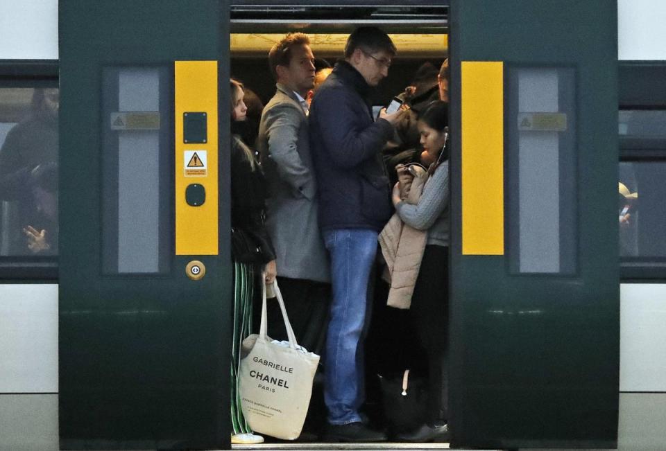 Commuters stand on a train waiting for their departure from Clapham Junction train station (AP)