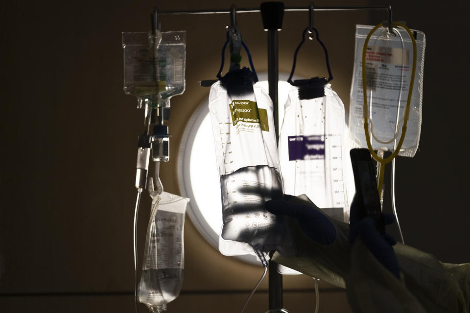 FILE - A nurse checks on IV fluids while talking to a COVID-19 patient at Providence Holy Cross Medical Center in Los Angeles, Dec. 13, 2021. When the end of the COVID pandemic comes, it could create major disruptions for U.S. health care. (AP Photo/Jae C. Hong, File)