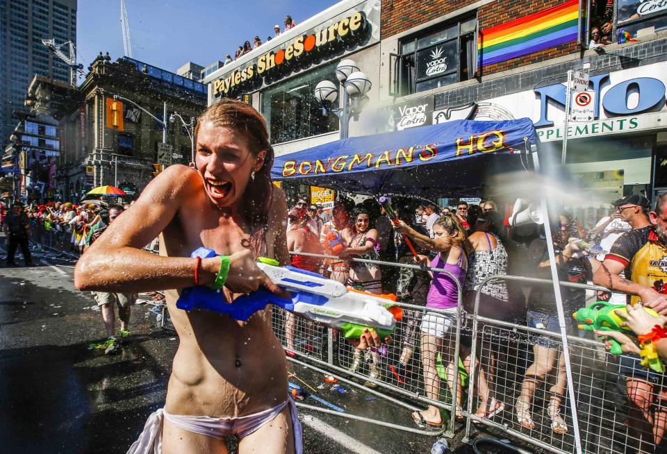 A topless woman gets sprayed by water guns during the 'WorldPride" gay pride Parade in Toronto