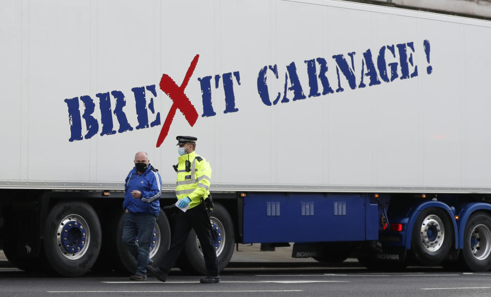 A policeman escorts the driver of a shellfish export truck as he is stopped for an unnecessary journey in London, Monday, Jan. 18, 2021, during a demonstration by British Shellfish exporters to protest Brexit-related red tape they claim is suffocating their business. The drivers were later stopped by police and issued with fines for an 'unnecessary journey' due to the national lockdown to curb the spread of the coronavirus. (AP Photo/Alastair Grant)