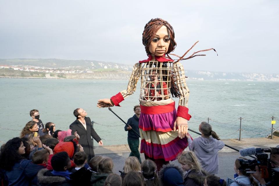 Actor Jude Law walks with Little Amal, a 3.5-metre-tall puppet of a nine-year-old Syrian girl, as it arrives at Folkestone Beach, Kent, as part of the Handspring Puppet Company’s The Walk (Gareth Fuller/PA) (PA Wire)