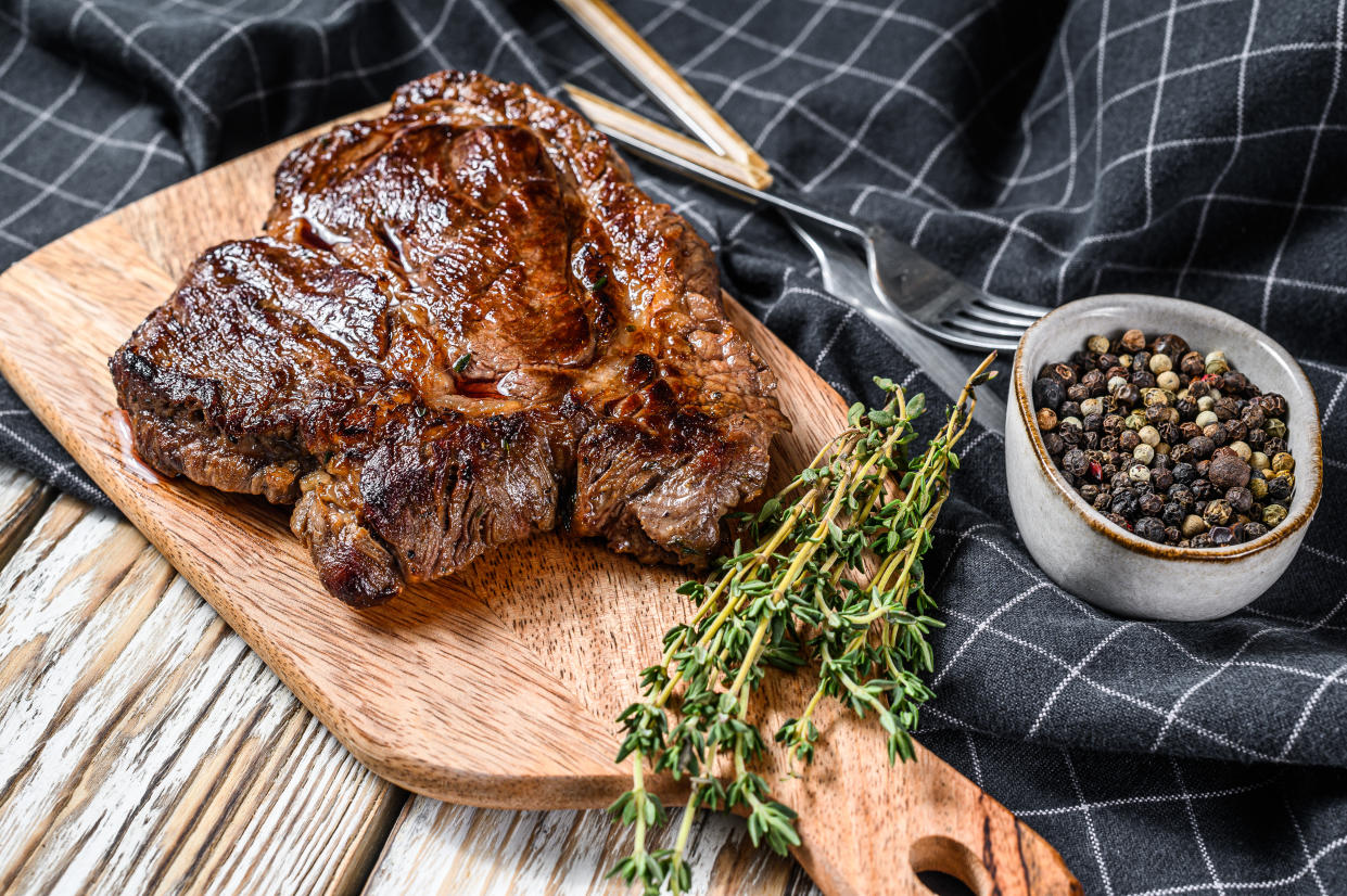 Grilled beef marbled steak. Chuck eye roll on the cutting Board. White background. Top view.