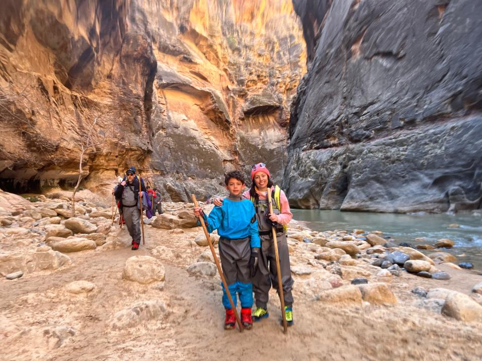 A mother and her son pose in hiking gear to wear in a river