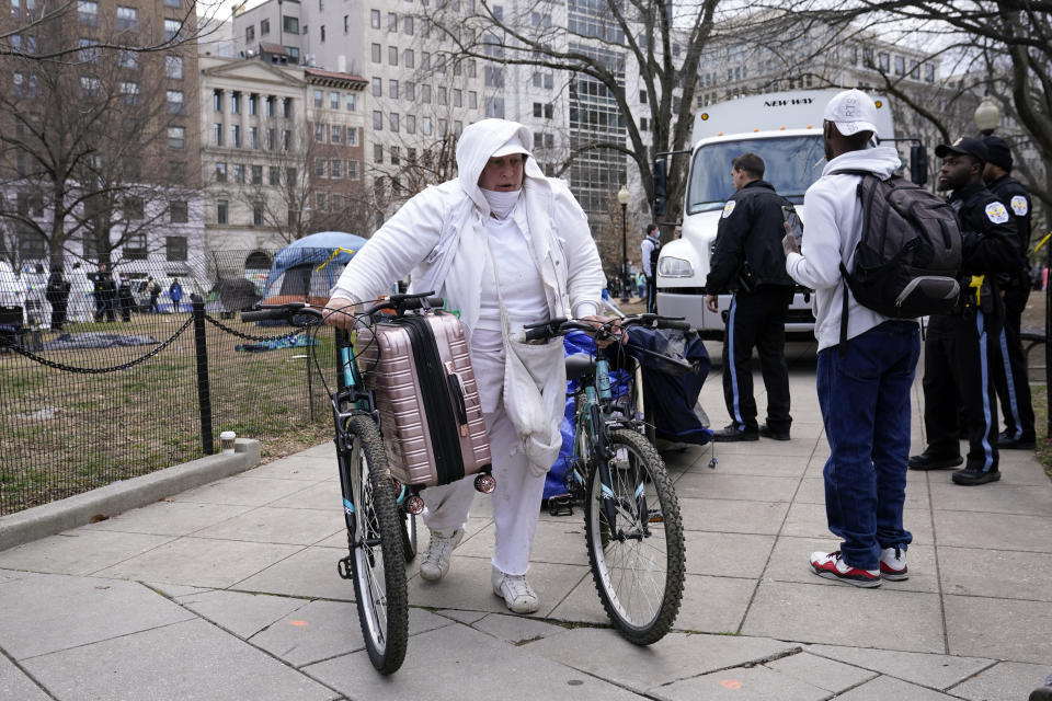 A woman carries belongings out of a homeless encampment at McPherson Square in Washington, Wednesday, Feb. 15, 2023, as it is cleared by the National Park Service. (AP Photo/Patrick Semansky)