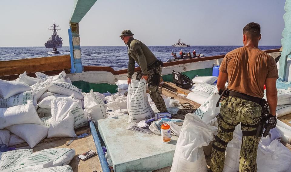 Guided-missile destroyer USS The Sullivans (DDG 68) and patrol coastal ship USS Hurricane (PC 3) sail in the background as Sailors inventory a large quantity of urea fertilizer and ammonium perchlorate discovered on board a fishing vessel intercepted by U.S. naval forces while transiting international waters in the Gulf of Oman, Nov. 9.