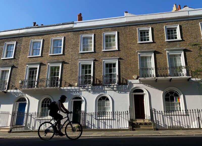 A cyclist rides past houses on a street in Islington, London