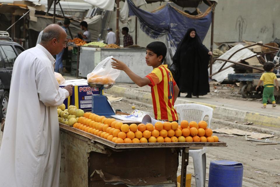 In this photo taken Friday, May 9, 2014, a shopper buy fresh fruit in Jamila market in Baghdad, Iraq. Fighting in Iraq’s western Anbar province, now in its fifth month, appears to have bogged down, with government forces unable to drive out Islamic militants who took over one of the area’s main cities. But the impact is being felt much further, with the repercussions rippling through the country’s economy to hit consumers and businesses. Fighting has also disrupted shipping, inflating prices of goods in Baghdad and elsewhere. (AP Photo/ Karim Kadim)