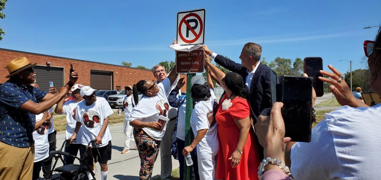 West Des Moines city officials and family of John and Barbara Long unveil a "Johnny E. Long, Jr. and Barbara Long Honorary Roadway" sign in Valley Junction on Friday.
