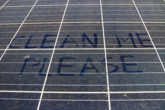 Solar panel with clean me please written on it.