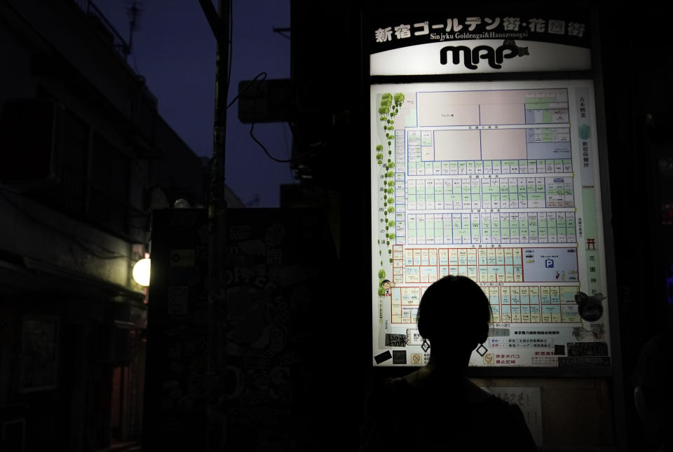 A tourist is silhouetted as she looks at the map of the Golden Gai in the Shinjuku district of Tokyo, July 28, 2019. (AP Photo/Jae C. Hong)