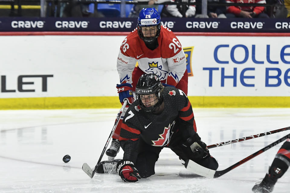 Canada forward Laura Stacey (7) falls to the ice in front of Czechia forward Vendula Pribylova (26) during the first period of a semifinal at the women's world hockey championships in Utica, N.Y., Saturday, April 13, 2024. (AP Photo/Adrian Kraus)
