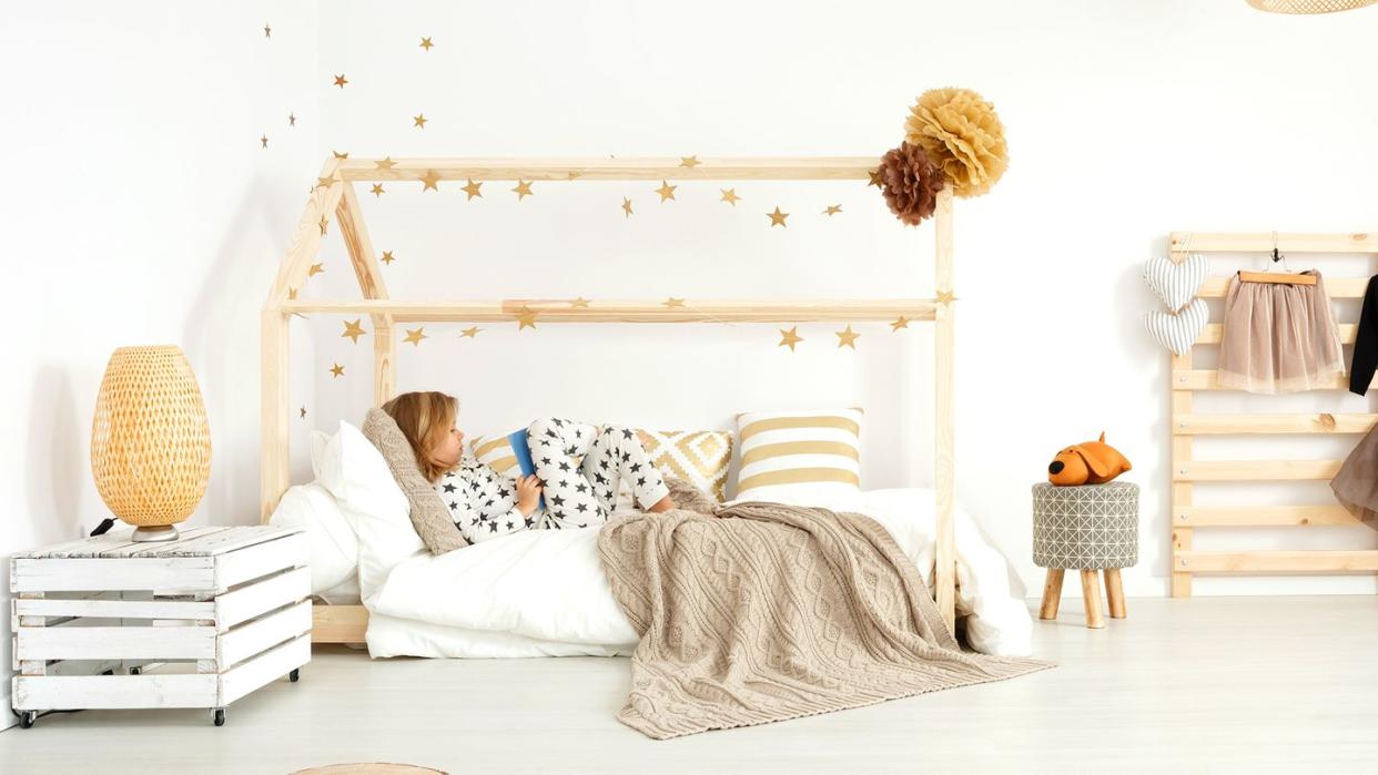 young kid reading in house frame montessori bed