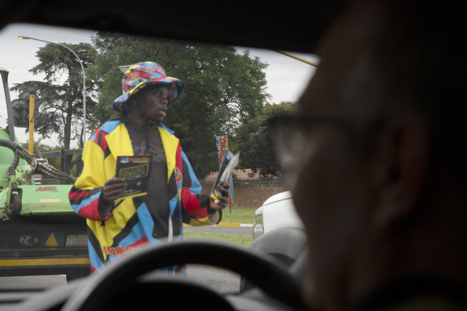 A man distributing pamphlets at a busy traffic intersection seen from a private security vehicle east of Johannesburg, South Africa, Tuesday, Nov. 28, 2023. Experts have warned that the South African police are losing the battle against crime and that has led those citizens who can afford it, to turn to a booming private security industry. (AP Photo/Denis Farrell)