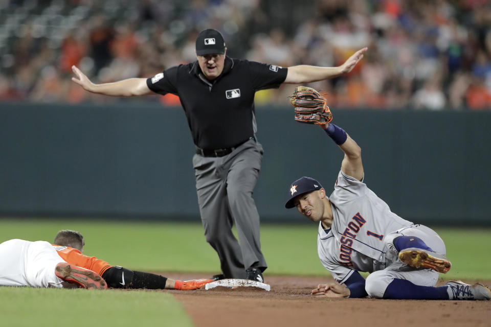 Houston Astros shortstop Carlos Correa, right, holds up the ball with his glove as Baltimore Orioles' Chris Davis keeps a hand on second base after a double, while umpire Mike Everitt makes the call during the sixth inning of a baseball game Saturday, Aug. 10, 2019, in Baltimore. (AP Photo/Julio Cortez)
