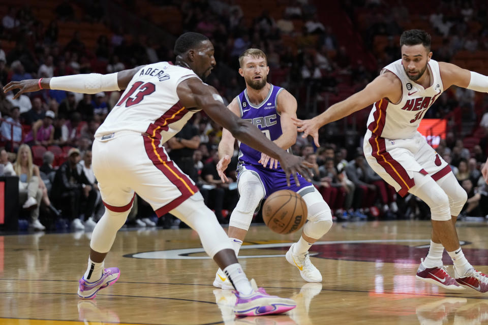 Sacramento Kings center Domantas Sabonis, center, passes past Miami Heat center Bam Adebayo (13) and guard Max Strus (31) during the first half of an NBA basketball game, Wednesday, Nov. 2, 2022, in Miami. (AP Photo/Wilfredo Lee)