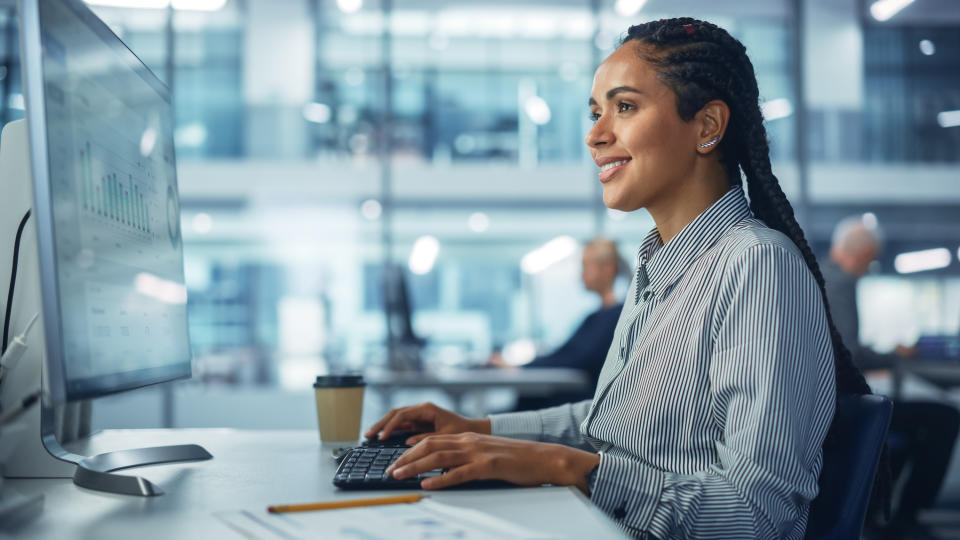 A woman smiles as she looks at her work computer