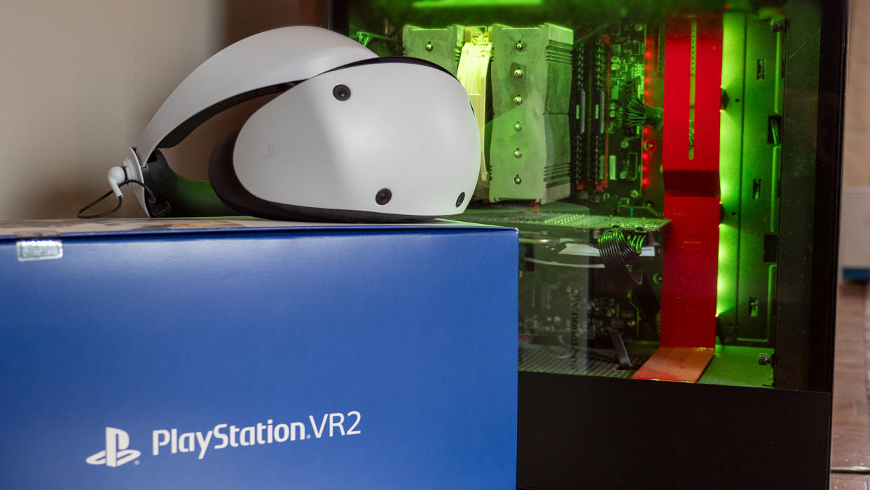  A PSVR 2 headset on top of its box next to a PC. 