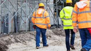 The backs of three builders as they walk away in a stock image