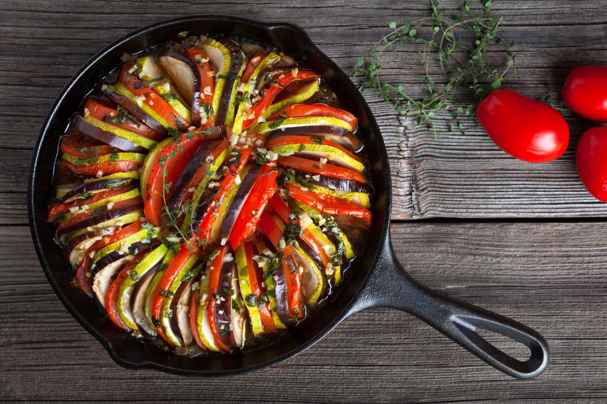 Vegetable ratatouille baked in cast iron frying pan traditional homemade healthy diet french vegetarian food on vintage wooden table background. Top view. Rustic style.