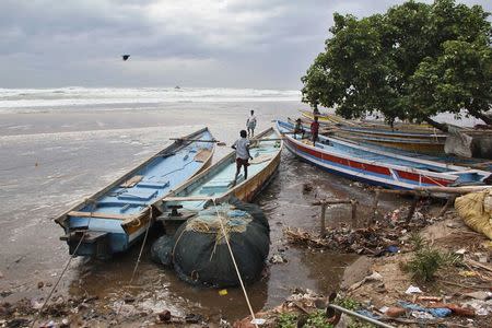 Boys walk on fishing boats by the shore before being evacuated, at Visakhapatnam district in Andhra Pradesh October 11, 2014. REUTERS/R Narendra