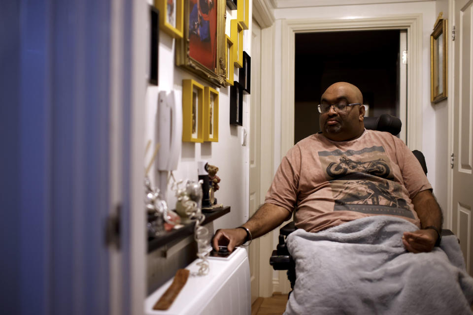 Thirugnanam Sureshan, 50, whose disabilities require round-the-clock care, adjusts a radiator thermostat as he discusses concerns about cost of living increases at his home in Bexhill, East Sussex, England, Wednesday, Nov. 9, 2022. Sureshan has a rare condition called Charcot foot which affects the bones, joints and tissues in his foot. He also has thyroid problems and an eye condition. Because of his condition, he doesn't cope well with the cold. (AP Photo/David Cliff)