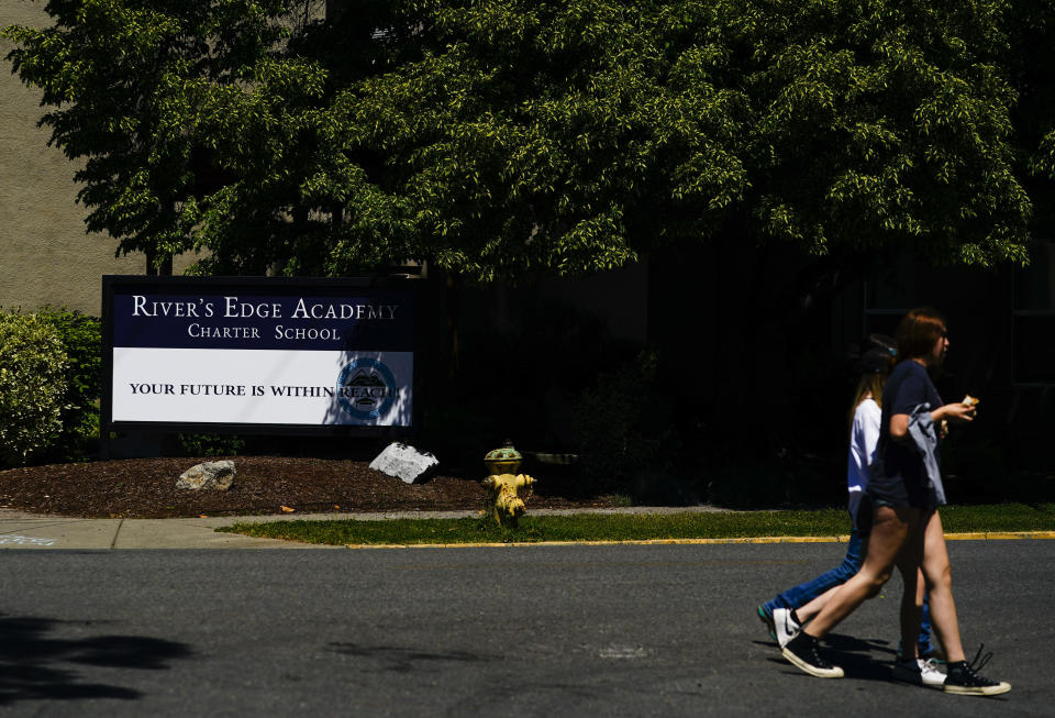 People walk by River's Edge Academy Charter School, which Khloe Warne now attends only one day a week, Thursday, May 18, 2023, in Grants Pass, Ore. Khloe, 12, was put on shortened school days by her school district after incidents in which she fought with students and threw a desk in outbursts her mother, Alyssa, attributes to a failure to support her needs. Now she only attends school one day a week for two hours, and hasn't been on a regular school schedule for years, instead spending much of her time at her mother's bakery or at the local library. (AP Photo/Lindsey Wasson)