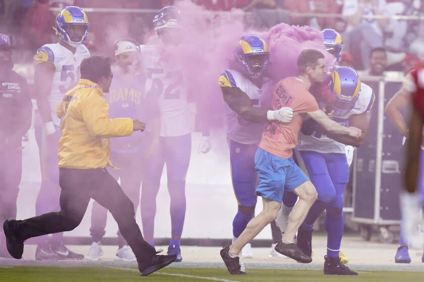 A protester is hit by Los Angeles Rams linebacker Bobby Wagner, right, and defensive end Takkarist McKinley during the first half of an NFL football game between the San Francisco 49ers and the Rams in Santa Clara, Calif., Monday, Oct. 3, 2022. (AP Photo/Godofredo A. Vásquez)