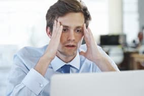 Shot of a frustrated young office worker sitting at his desk and working on a laptop