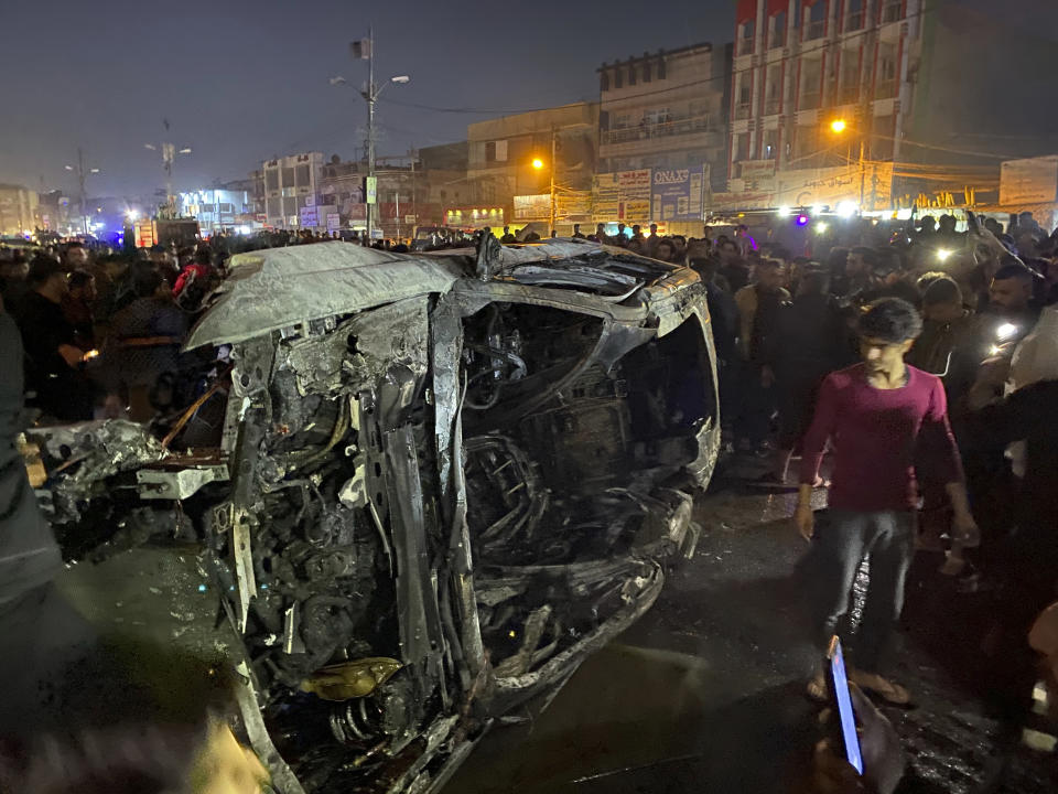 Iraqis gather at the site of a burned vehicle targeted by a U.S. drone strike in east Baghdad, Iraq, Wednesday, Feb. 7, 2024. (AP Photo/Hadi Mizban)