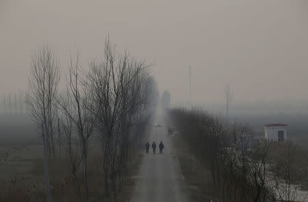 FILE PHOTO: People walk along a village road on a polluted day after the Chinese Lunar New Year holidays on the outskirts of Langfang, Hebei province, China, February 3, 2017. REUTERS/Jason Lee/File Photo