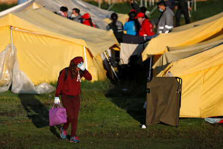 A Venezuelan migrant girl carries her belongings out of a tent inside a temporary humanitarian camp that is closed by the government, in Bogota, Colombia January 15, 2019. REUTERS/Luisa Gonzalez