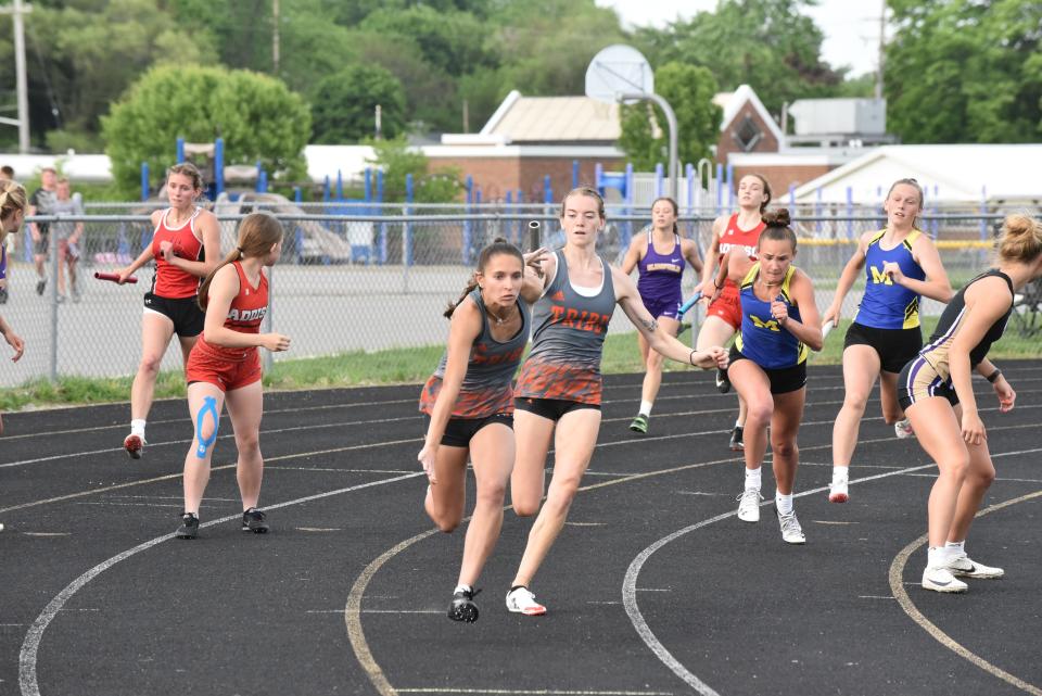 Tecumseh's Dakota Schlorf receives the baton from Jordyn Wright during the 4x100-meter relay at the Lenawee County Track and Field Championships at Onsted.