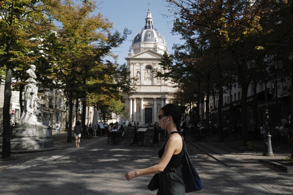 A woman wearing a face mask walks past the Sorbonne university in Paris, France, Thursday, Sept. 17, 2020. In France, overcrowded universities have seen the emergence of at least a dozen of virus hotspots, raising concerns in a country where the number of infections has steadily increased in recent weeks. (AP Photo/Francois Mori)