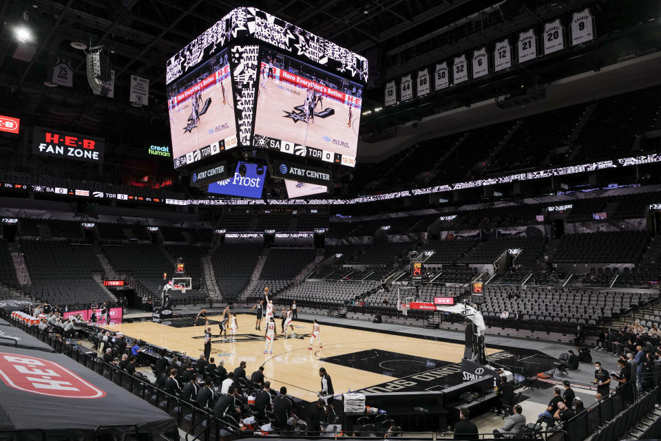 The Toronto Raptors and San Antonio Spurs tip off at the start of an NBA basketball game, Saturday, Dec. 26, 2020, in San Antonio. As a precaution intended to prevent the spread of COVID-19, there were no spectators allowed. San Antonio won 119-114. (AP Photo/Darren Abate)