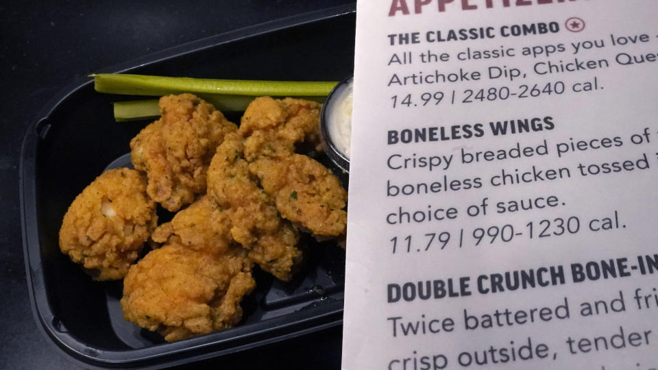 An order of "boneless wings" rests on a counter, along with the menu description, Tuesday, Feb. 7, 2023, in Derry, N.H. With the Super Bowl at hand, behold the cheerful untruth that has been perpetrated upon (and generally with the blessing of) the chicken-consuming citizens of the United States on menus across the land: a “boneless wing” that isn’t a wing at all. (AP Photo/Charles Krupa)