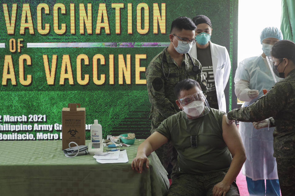 Philippine Army commander, Lt. Gen. Jose Faustino Jr., front left, is injected with the Sinovac vaccine from China during the start of vaccination at Fort Bonifacio, Metro Manila, Philippines on Tuesday, March 2, 2021. The Philippines launched a vaccination campaign to contain one of Southeast Asia's worst coronavirus outbreaks but faces supply problems and public resistance, which it hopes to ease by inoculating top officials. (AP Photo/Aaron Favila)