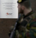 In this photo taken on Wednesday, Feb. 22, 2017, a soldier walks by a memorial plaque for victims of the attack at Zaventem Airport in Brussels. One year after the March 22, 2016 Brussels attacks, the city's physical scars may have healed, but the pain is still apparent beneath the surface. (AP Photo/Virginia Mayo)