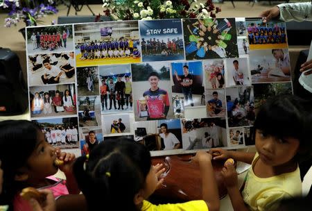 Children look at pictures before relatives and friends pray for the 12 schoolboys and their soccer coach trapped inside a flooded cave, at Mesai Grace Church in the northern province of Chiang Rai, Thailand, July 8, 2018. REUTERS/Soe Zeya Tun