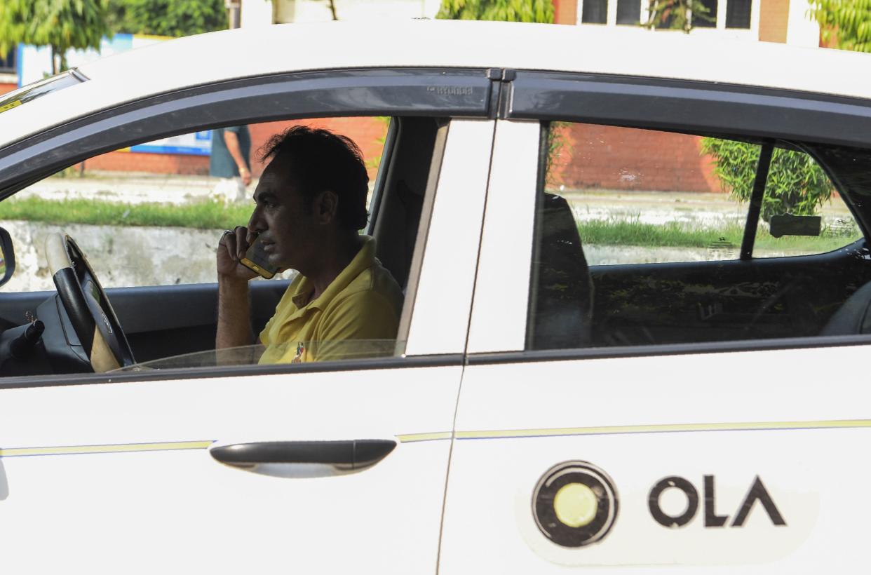 In this photograph taken on September 12, 2019, an Ola cab driver talks on his mobile phone at a roadside in Amritsar. - When India's Finance Minister Nirmala Sitharaman September 10 claimed millennials' preference for ride-hailing apps was contributing to a painful slump in car sales, it sparked a online backlash from furious youngsters. While data shows ride-hailing firms such as Uber and Ola are popular with younger consumers more comfortable with shared mobility and digital trends, analysts say the auto industry's problems run deeper than that -- and it is facing more serious bumps in the road. (Photo by NARINDER NANU / AFP) / TO GO WITH 'INDIA-TRANSPORT-AUTOMOBILE-ECONOMY', FOCUS BYGLENDA KWEK WITH ARCHANA THIYAGARAJAN        (Photo credit should read NARINDER NANU/AFP via Getty Images)